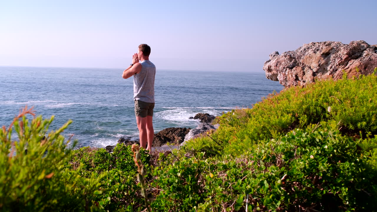 Fit young man on coastal cliff lookout at sunrise finished with meditative flow