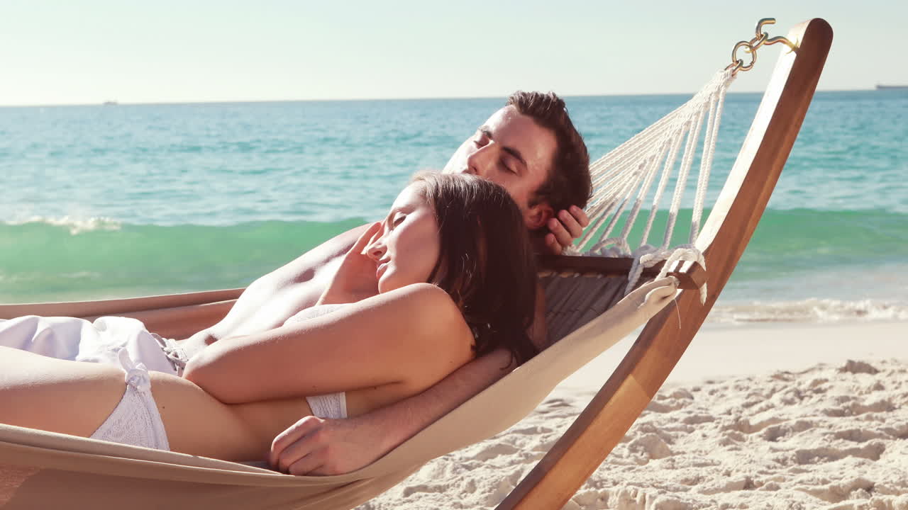 una pareja relajándose en una hamaca en la playa.