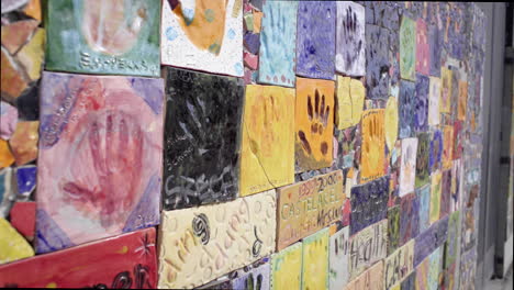 colorful mosaic wall with handprint tiles