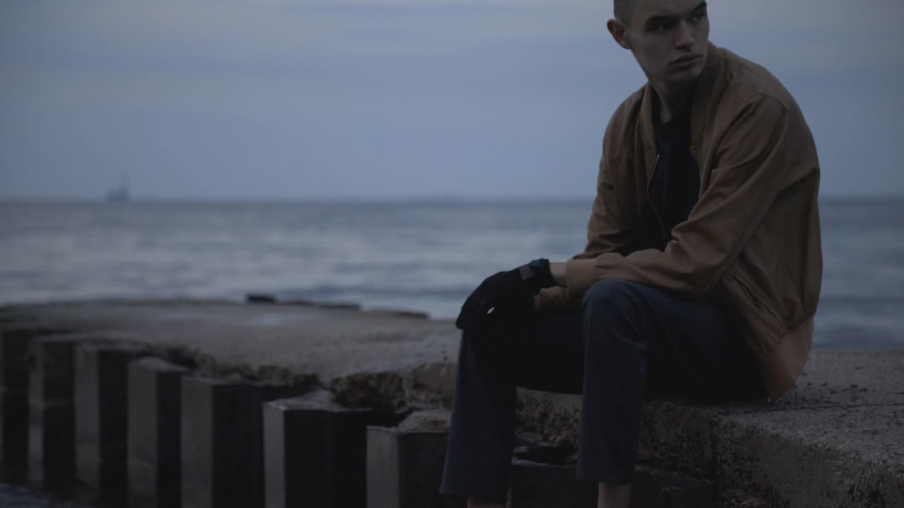 A Sad Young Man Sitting While Looking On The Surrounding In Canada - Wide Shot