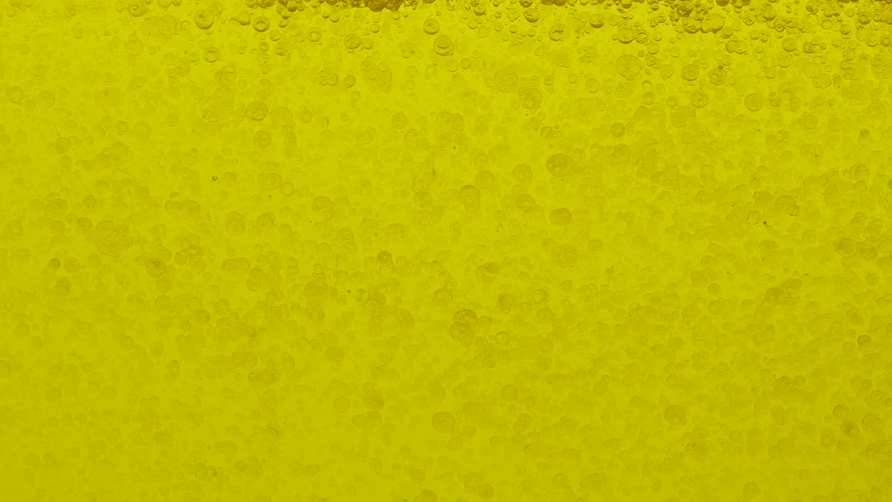 수백 개의 기름 공이 노란색 액체에서 움직입니다.