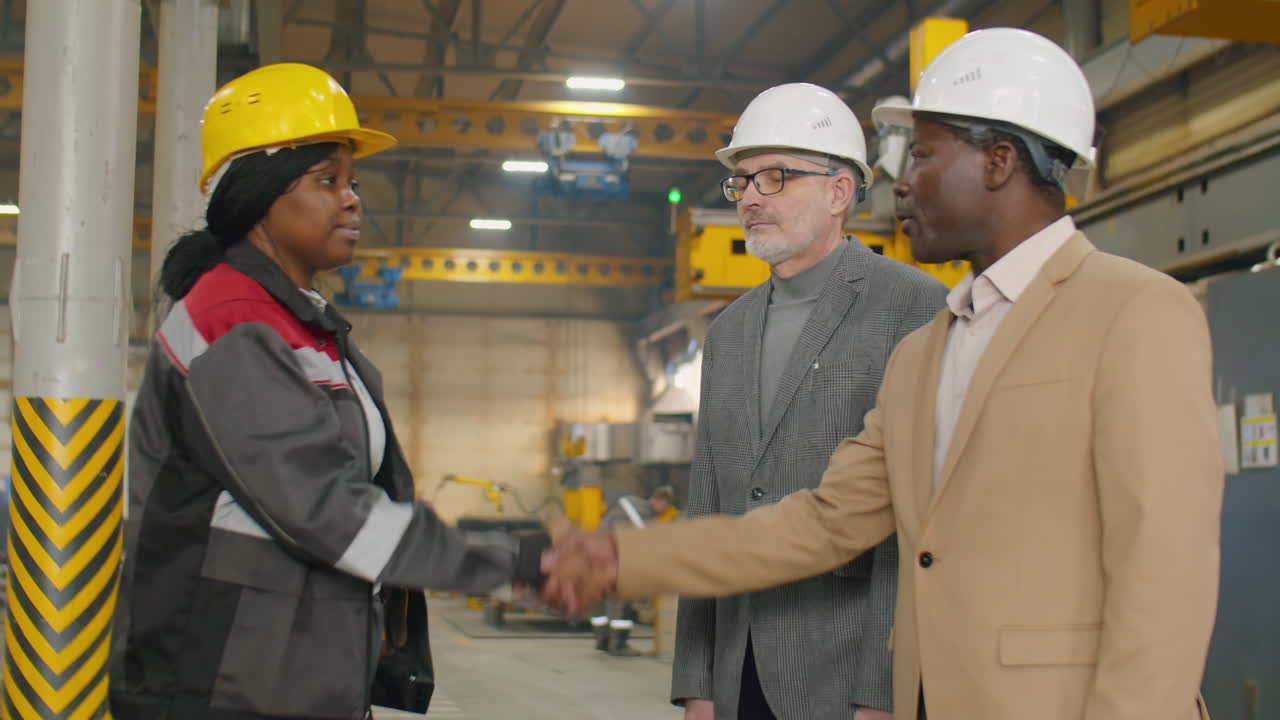 Female Factory Worker Greeting Inspectors with Handshake