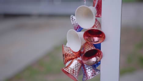 Close-Up-Of-Colorful-Ornamental-Bells-Hanging-On-White-Post