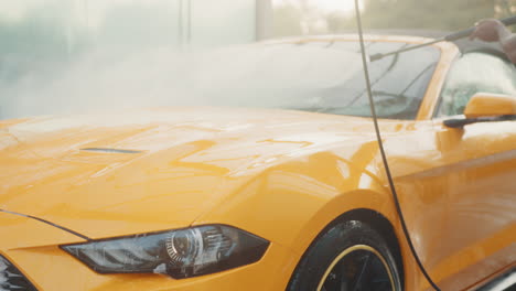 man washing a yellow convertible car at a car wash