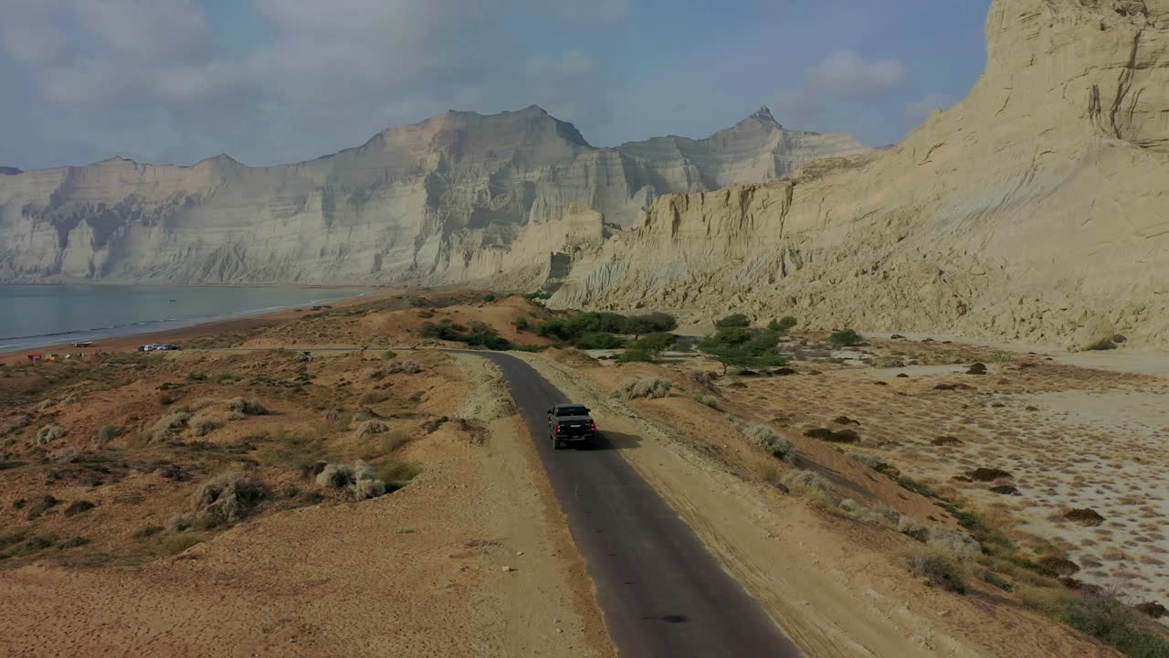 balochistan의 해안선 옆 도로를 따라 운전하는 4x4 트럭의 항공 보기