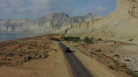 aerial view of 4x4 truck driving along road beside coastline in balochistan