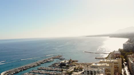 Drone-shot-panning-along-the-horizon-from-thesea-to-land-in-Marbella,-Spain