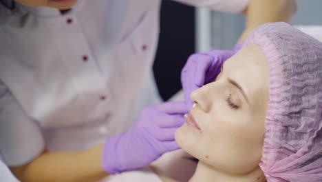 a specialist in aesthetic cosmetology holds a syringe in her hand and makes botox injections to the lips for the client. close-up.