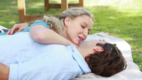 a smiling couple lie together on the ground as they then look at the camera