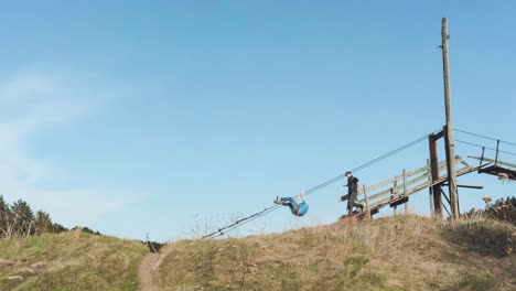 people enjoying a rope swing on a hilltop