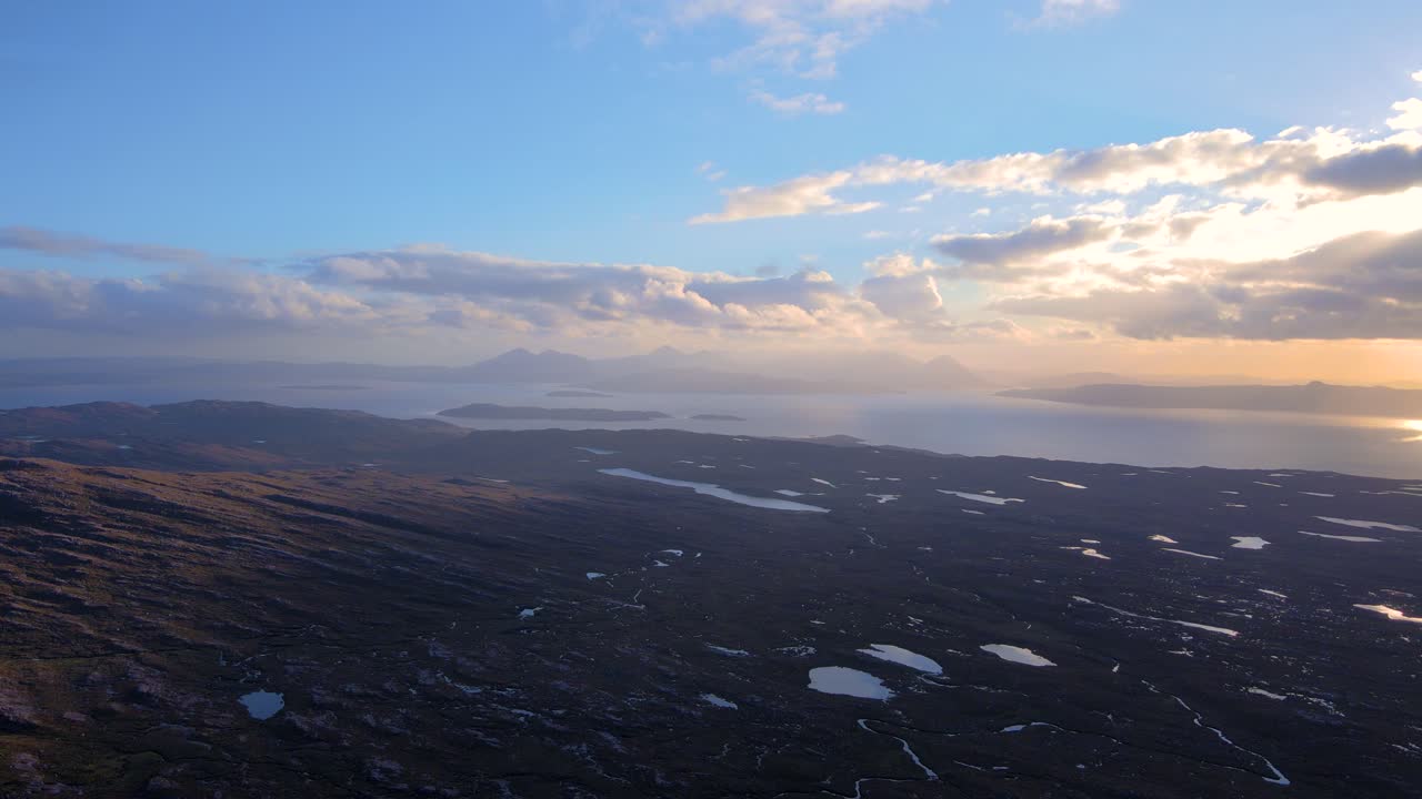 Drone shot flying from the Bealach na Bà pass towards the Isle of Skye in the Scottish highlands at sunset.
