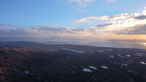 drone shot flying from the bealach na bà pass towards the isle of skye in the scottish highlands at sunset.