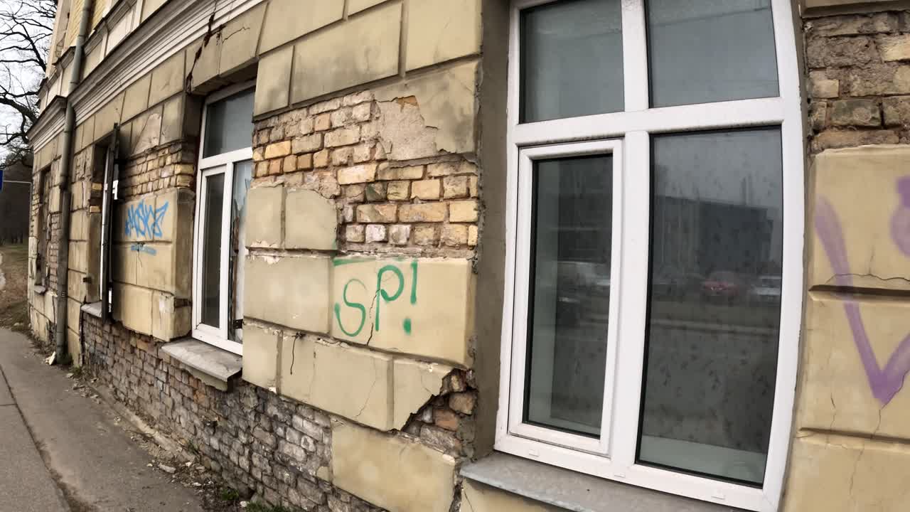 Urban street view of a building wall with graffiti. Crumbling stone colored wall.