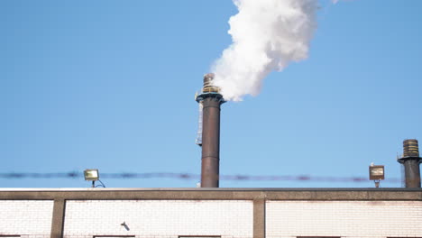 smoke pouring from smoke stack on top of building