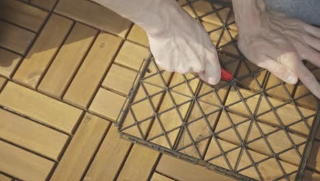 person cutting interlocking decking tiles into two pieces