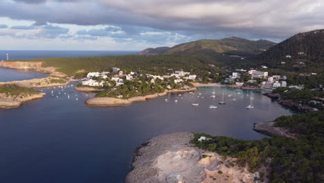 aerial view of portinatx village, blue sea and boats on ibiza, spain.