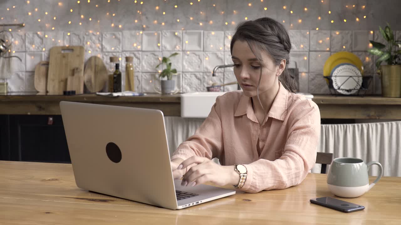 mujer trabajando desde casa en una computadora portátil en una cocina