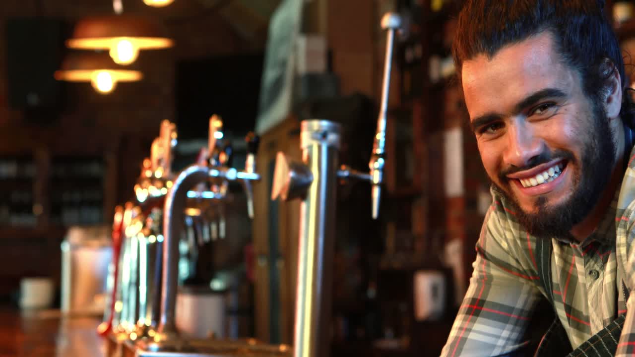retrato de un barman sonriente apoyado en el mostrador de la barra