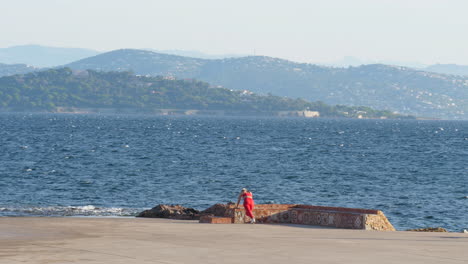 Gesunde-Frau-Macht-Übungen-Vor-Dem-Meer,-Rote-Leggings,-Attraktive-Blondine