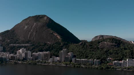Schneller-Luftschwenk-Um-Den-Stadtsee-Lagoa-Rodrigo-De-Freitas-In-Rio-De-Janeiro,-Der-Die-Bergige-Umgebung-Mit-Dem-Corcovado-Und-Den-Two-Brothers-Mountains-Sowie-Das-Viertel-Ipanema-Zeigt