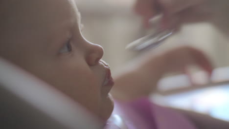 baby girl with messy face having cereal for breakfast