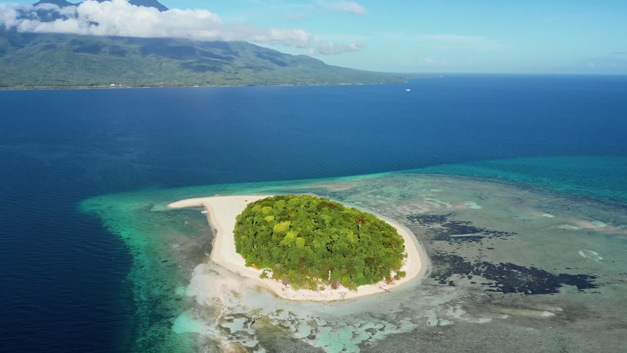 Vista aerea con drone di una piccola isola tropicale circondata dall'oceano turchese e dalle barriere coralline nelle Filippine. Spiagge di sabbia bianca e una fitta vegetazione verde creano un paradiso insulare incontaminato.