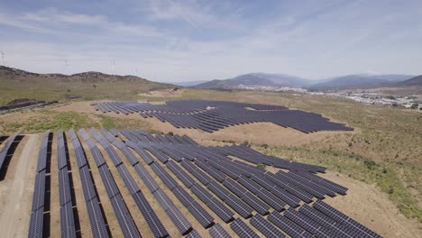 Rows-of-solar-panels-in-massive-photovoltaic-plant,-aerial-flyover