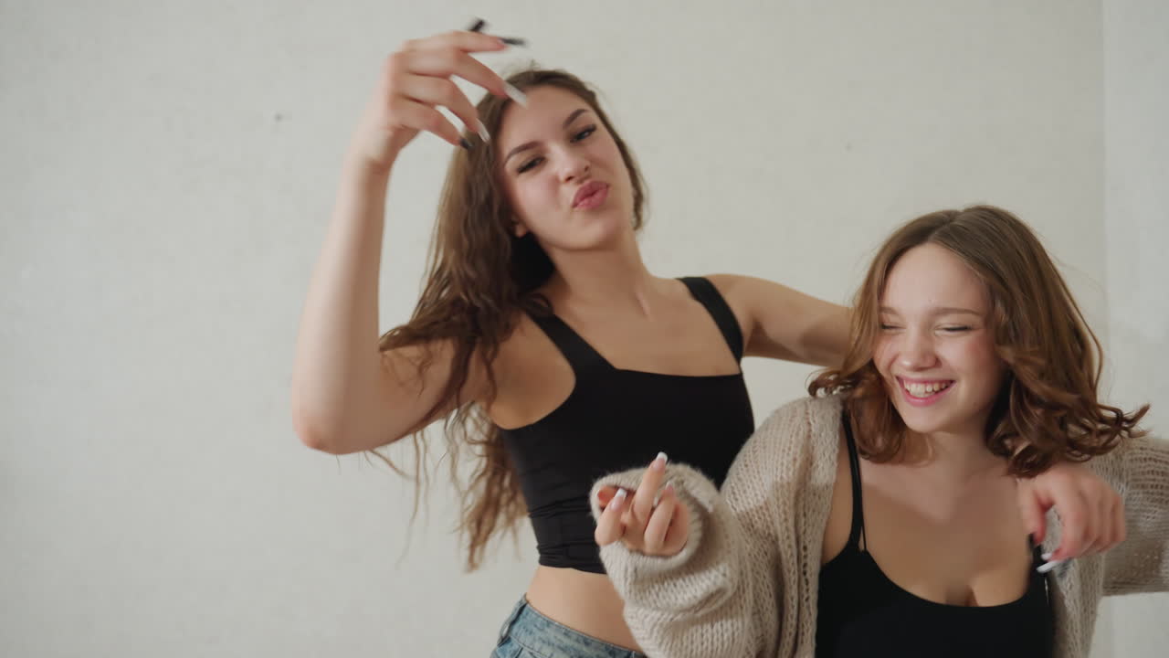 Amigos caucásicos bailando despreocupadamente en un dormitorio, movimientos enérgicos y juguetones con sacudidas de pelo y sonrisas, ritmo alegre en ropa casual, coreografía natural y expresiones alegres, luz natural cálida