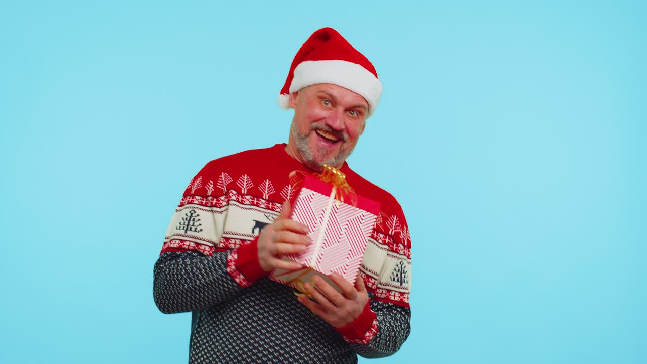Cheerful man in sweater santa christmas hat getting present gift box expressing amazement happiness