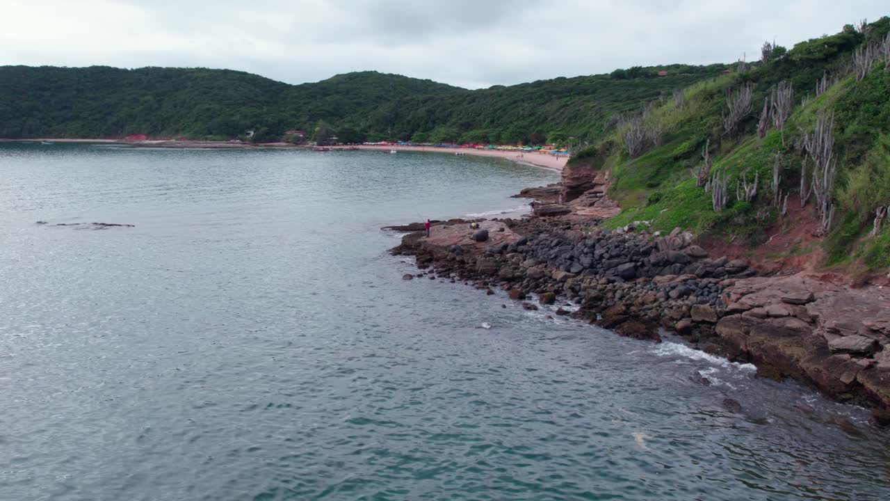 Aerial view establishing of a fisherman in the foreground with Tartaruga beach in the background, B&uacute;zios, Brazil