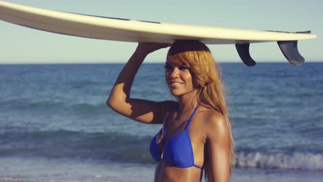 mujer africana sexy sosteniendo una tabla de surf por encima de la cabeza