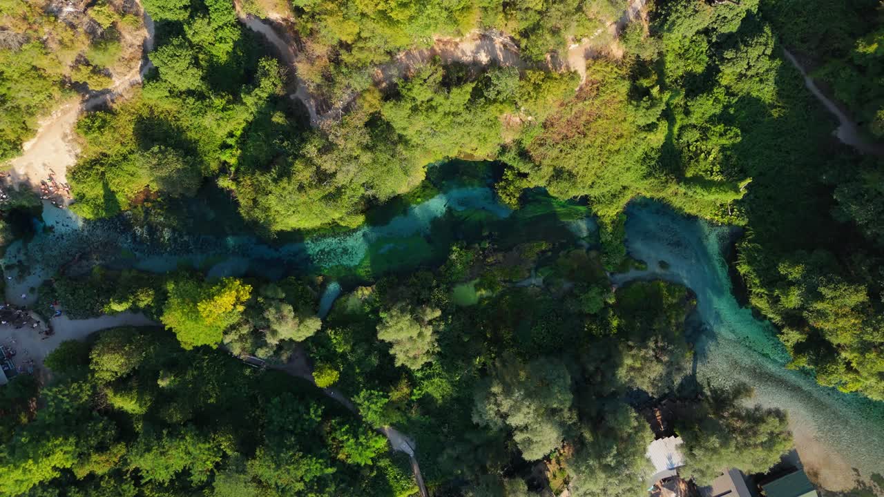 La sorgente dell'Occhio Blu circondata da una lussureggiante foresta verde e sentieri tortuosi in Albania, vista aerea