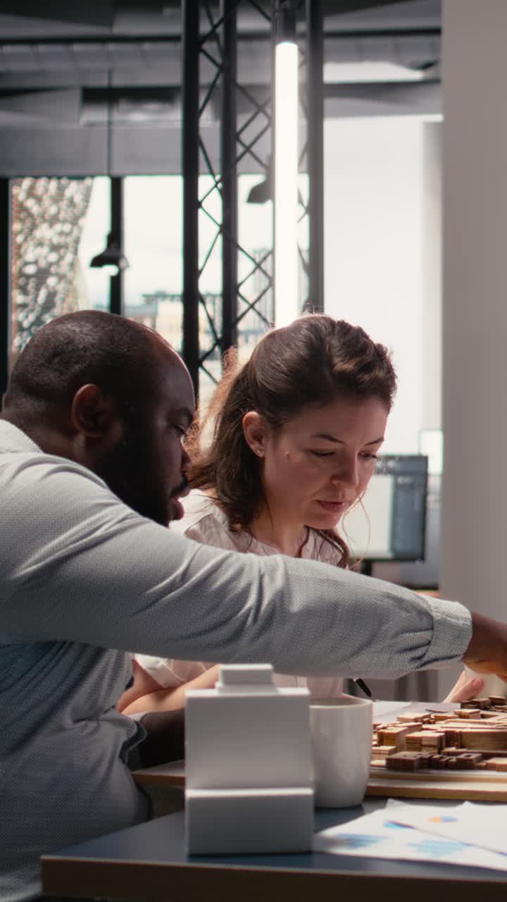 Vertical Video Real estate professionals engage in meeting to review blueprints and 3D models