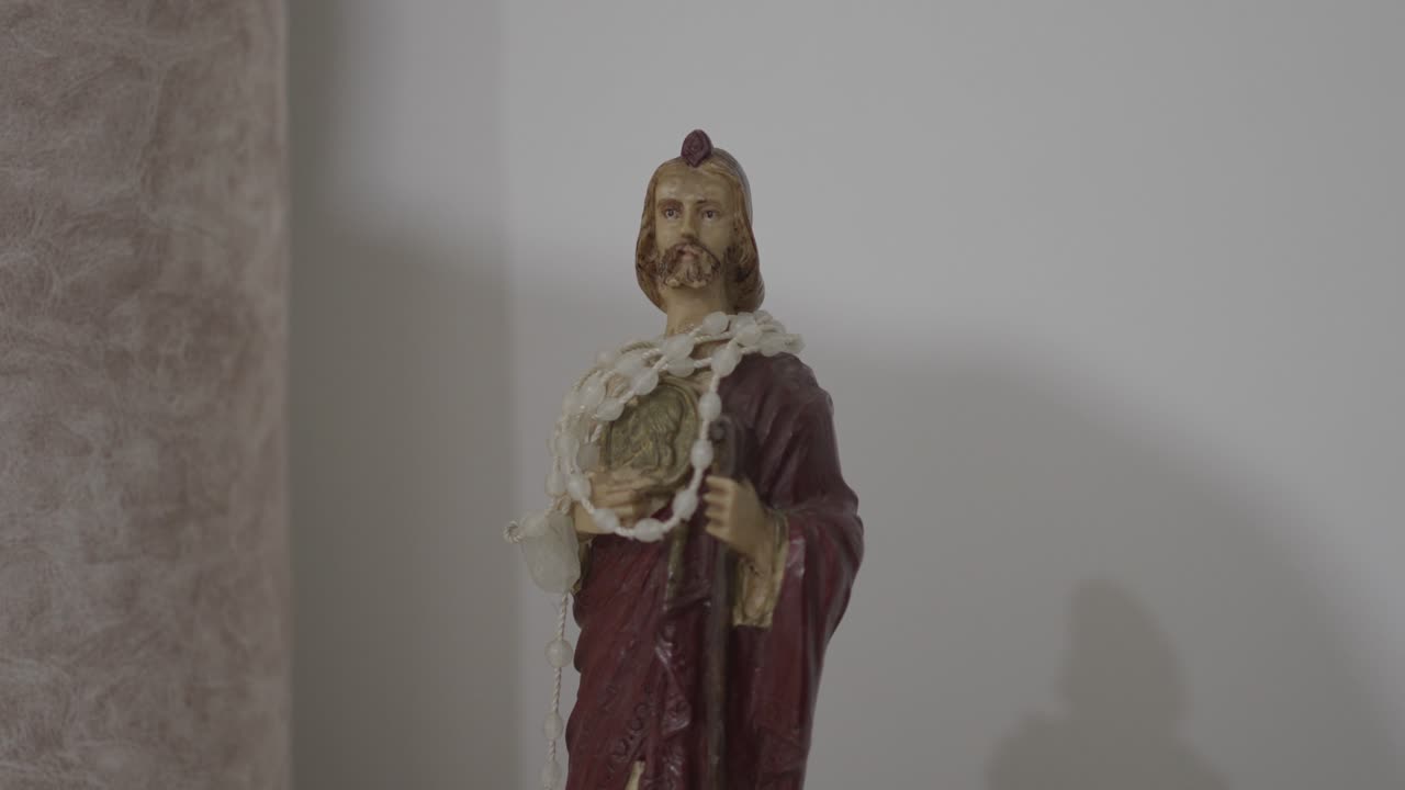 Statua di un santo cattolico esposta all'interno di una chiesa con un simbolo devozionale.