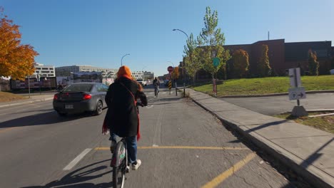 woman cycling on city street with cars and buildings