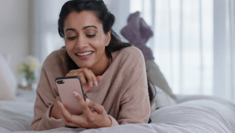 Hermosa-Mujer-Usando-Un-Teléfono-Inteligente-Enviando-Mensajes-De-Texto-Navegando-Por-Mensajes-De-Redes-Sociales-Disfrutando-De-La-Comunicación-Por-Teléfono-Móvil-Acostada-En-La-Cama-En-Casa