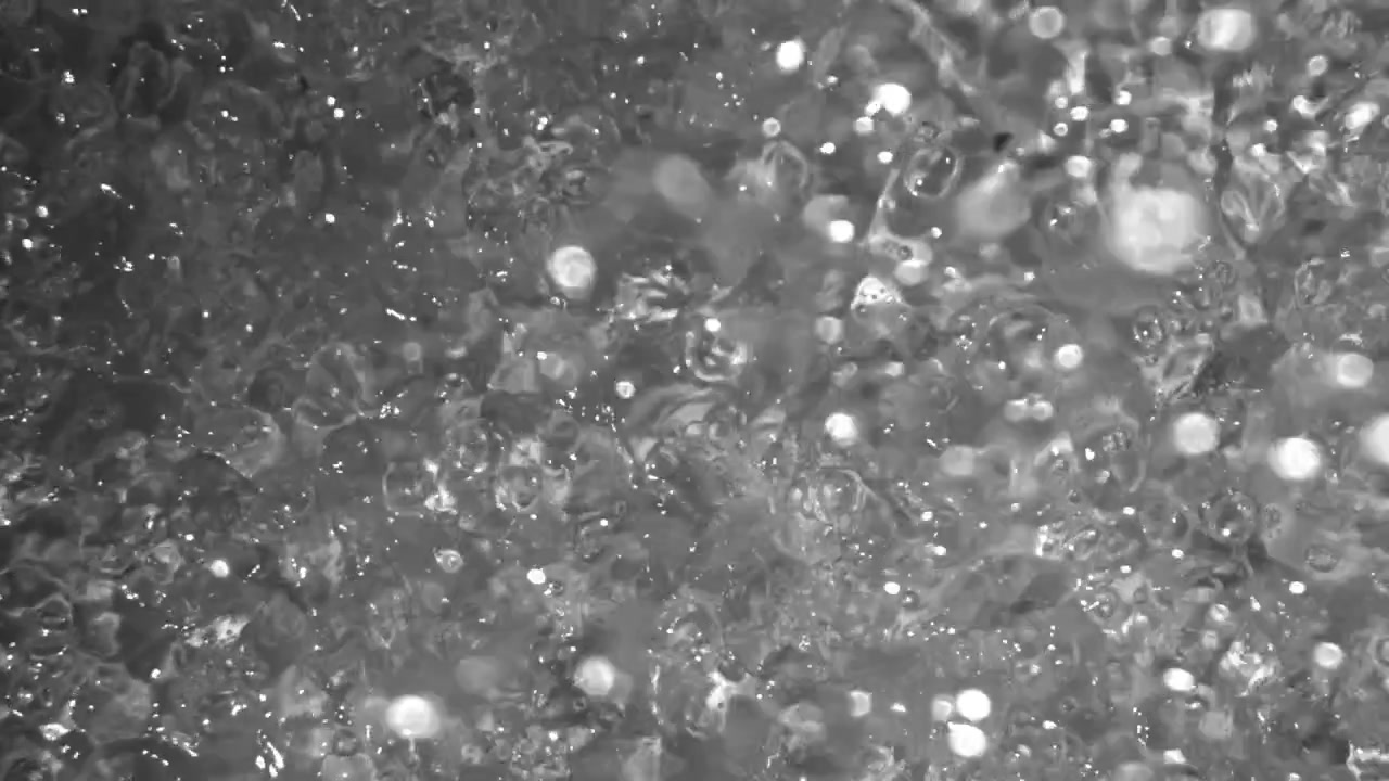 Superficie d'acqua monocromatica con bolle e riflessi di luce bokeh