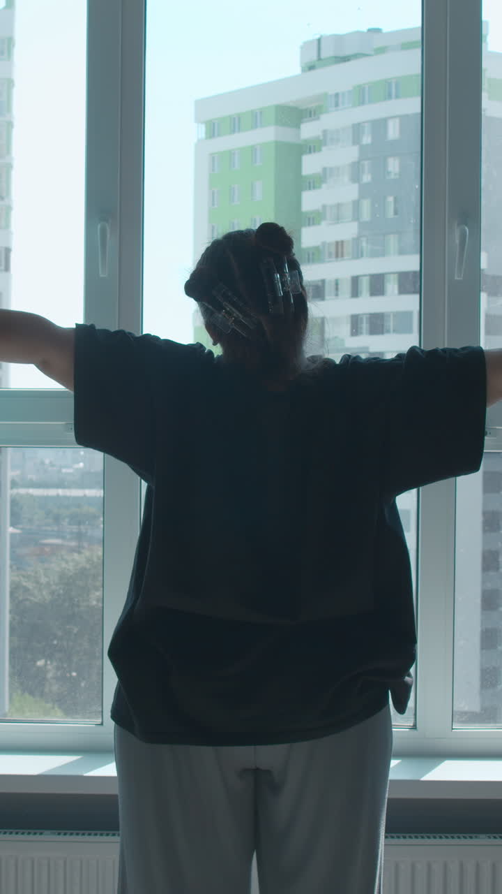 mujer estirándose por la ventana