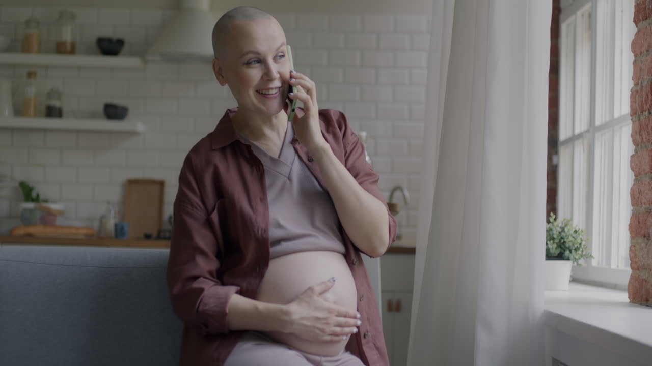Pregnant woman talking on the phone in the kitchen