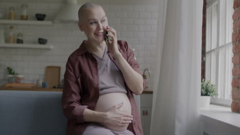 pregnant woman talking on the phone in the kitchen