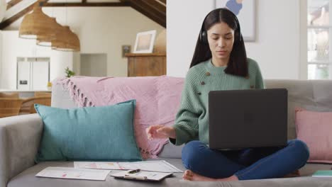 Biracial-woman-using-laptop-and-working-in-living-room