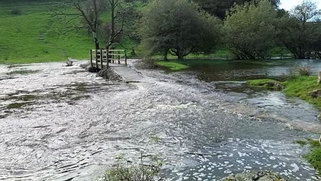 slow motion saturated north wales countryside stream burst its banks with submerged trees after storm weather