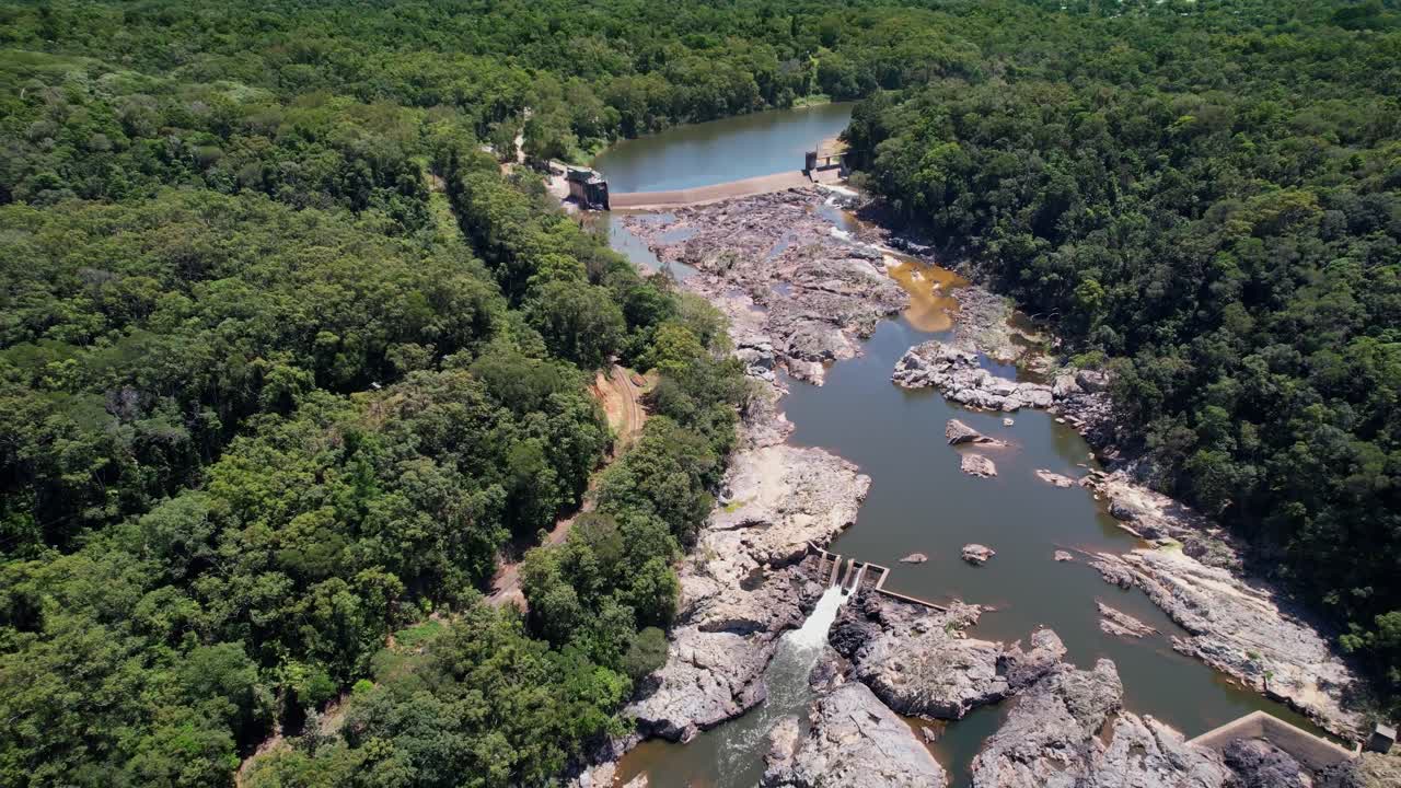 Lush forest surrounds river dam at Barron Falls, scenic rail nearby, peaceful vibe