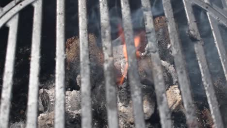 camera-rotate-over-outdoor-grill-bars-closeup-showing-flames-and-smoke-from-burning-charcoal-and-wood