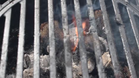 camera rotate over outdoor grill bars closeup showing flames and smoke from burning charcoal and wood