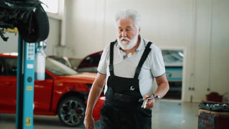 old man looking on a tool cart and searching for detail while working in workshop