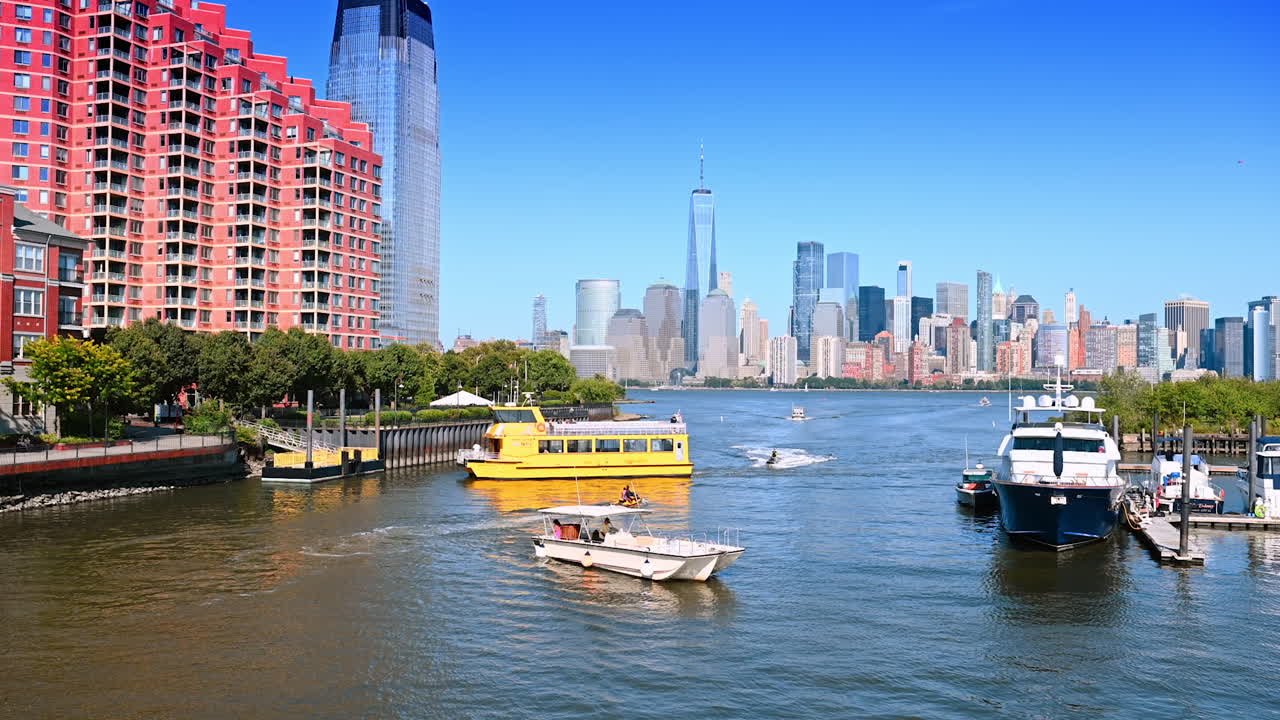 Yellow boat approaches the quay at the Hudson River. Diverse water vehicles are on the waterscape. Skyline of Manhattan at backdrop