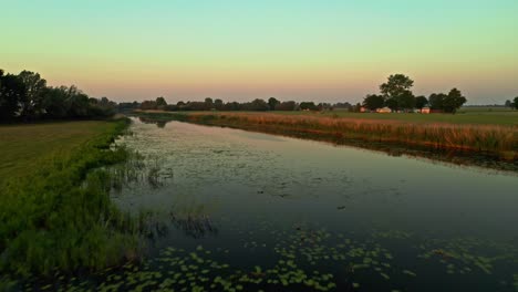 Splendid-Drone-Aerial-Low-Flying-shot-above-reflective-lake-at-sunrise---marshland-in-Poland