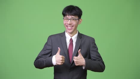 young happy asian businessman smiling while giving two thumbs up