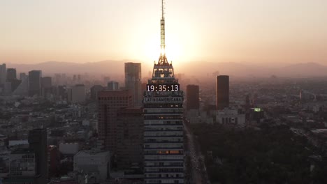 aerial jib down shot of a big skyscraper with the sun behind at sunset in mexico city